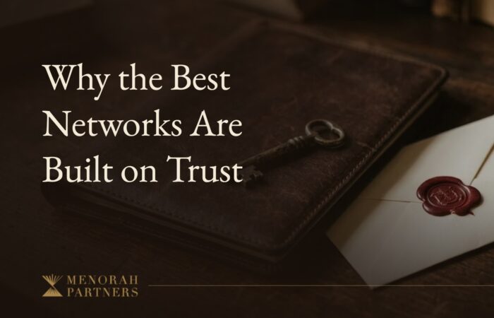 A brass key resting on a closed leather portfolio beside a wax-sealed envelope on a dark wooden desk, with the title “Why the Best Networks Are Built on Trust” and the Menorah Partners logo